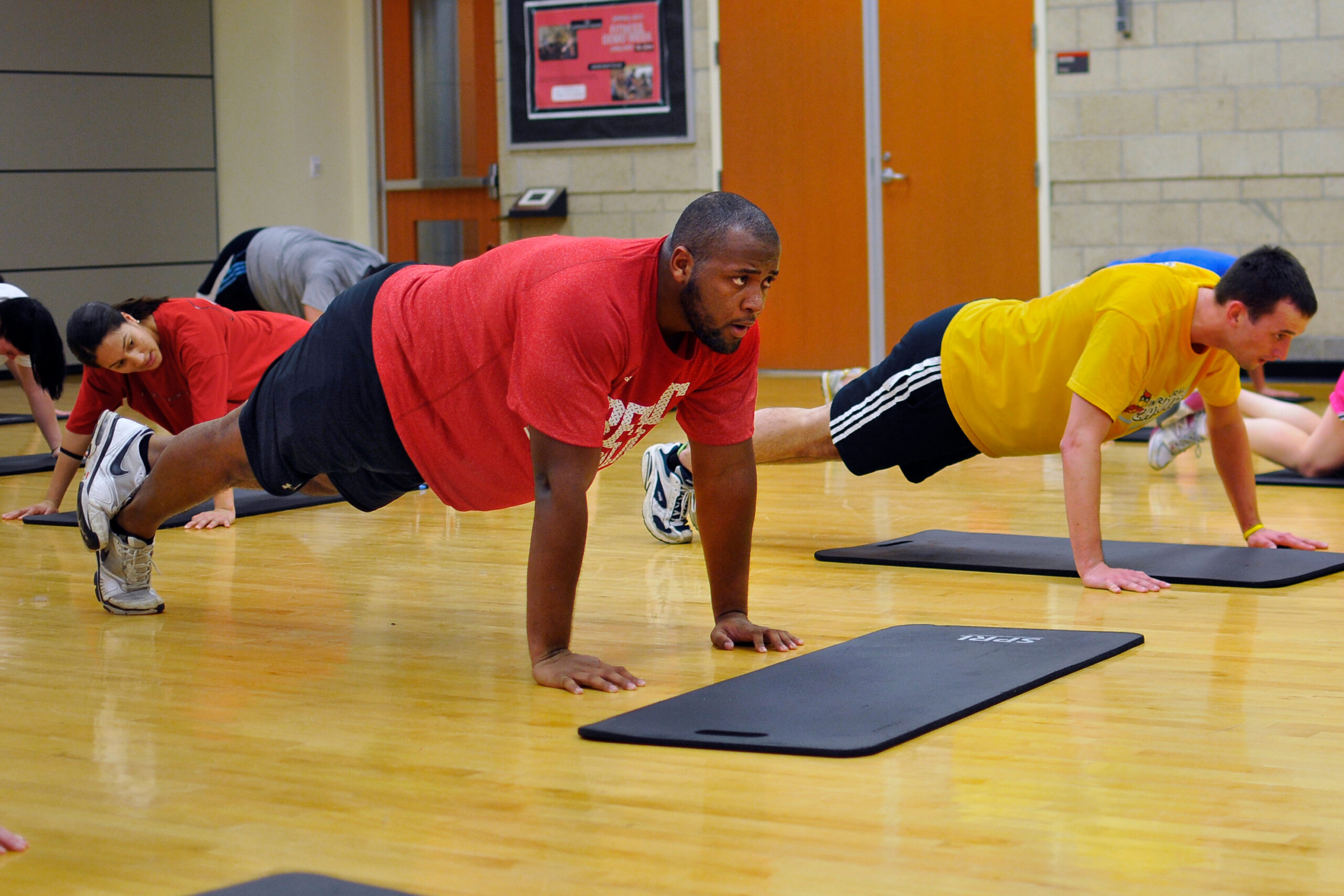 Students hold plank positions in a gym. 